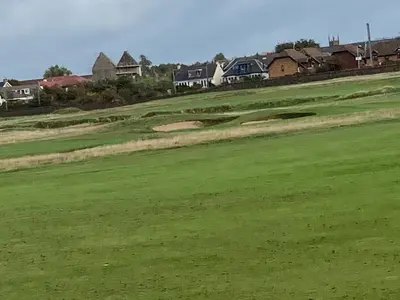a view of a golf green with houses in the background at The Bunker, Golf Cottage in Prestwick