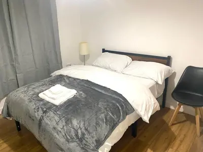 a bed with white sheets and a chair in a room at Charming home away from home! in Edinburgh