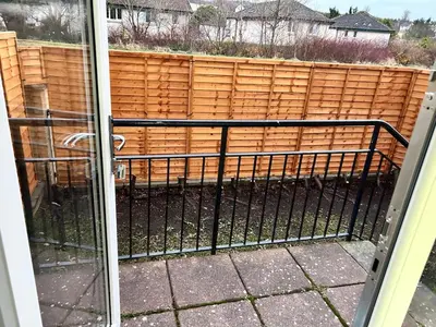 a dog behind a gate on a fence at Charming home away from home! in Edinburgh