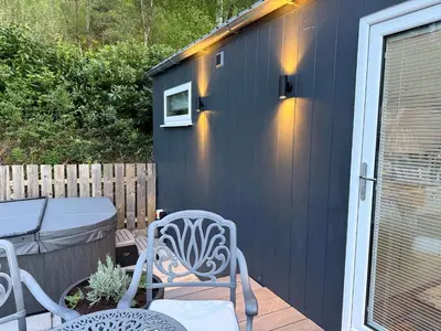 a blue shed with two chairs and a table at Tumpseys Hideaway with Hot Tub & Sunset Loch Views, Glencoe Near Fort William in Ballachulish