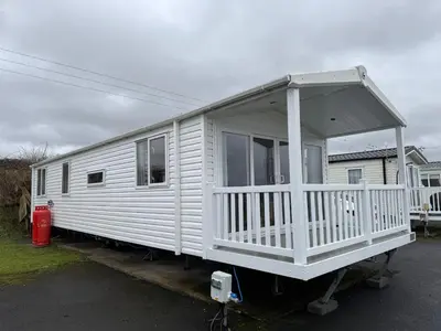 a white house with a porch on the back of it at The Retreat - Turnberry Holiday Park Amazing Sea View in Girvan