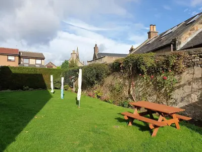 a picnic table in the grass next to a wall at Modern flat near Murrayfield stadium, sleeps 4 in Edinburgh