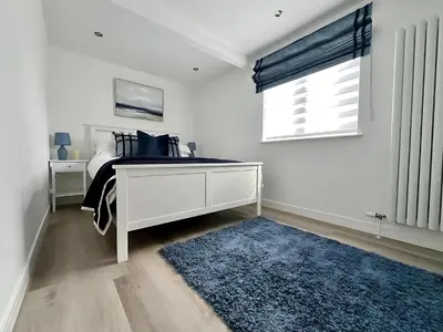 a bedroom with a bed with a blue rug and a window at Dunmuir House 4 Bedroom 2 bathroom House & Garden in Denny in Falkirk