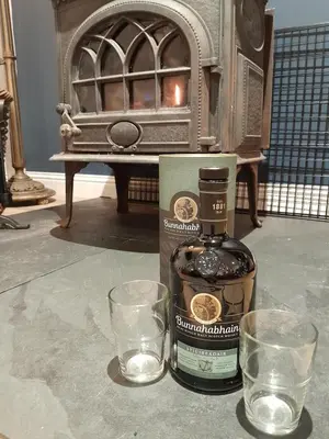 a bottle of whiskey and two glasses on a table at Wee Blue Hoose in Dalmally
