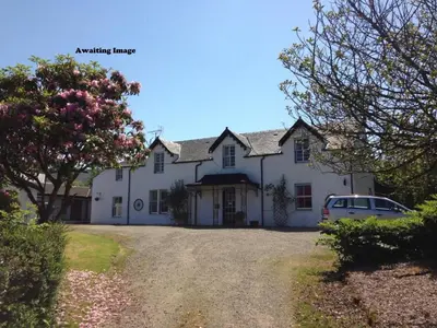 a white house with a car parked in the driveway at Strathwhillan House in Brodick