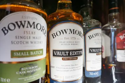 a group of bottles of whisky on a shelf at Lochside Hotel in Bowmore