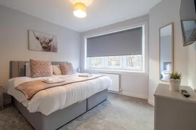 a bedroom with a large bed and a window at Kerr Apartment-Spacious 4-Bed Flat in Hamilton, Close to Glasgow in Cadzow
