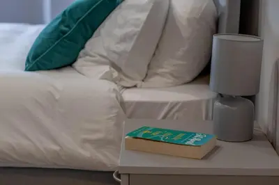 a book sitting on a table next to a bed at Kerr Apartment-Spacious 4-Bed Flat in Hamilton, Close to Glasgow in Cadzow