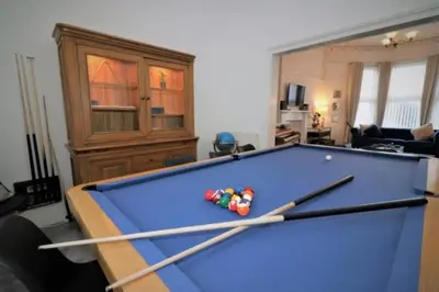 a pool table in a living room with two cues at 10 Bedrooms Pool Table Garden Piano in Glasgow