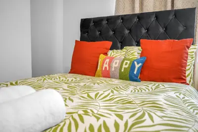 a bed with colorful pillows on top of it at 3 Bedrooms Homely House in Motherwell Sleeps 8 comfortably with 6 double beds Near Glasgow Edinburgh Free Private Parking Business Travellers Contractors Holiday Goers Near all Major transport links in Carfin