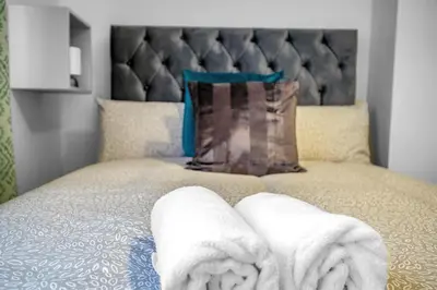 a bed with two towels on top of it at 3 Bedrooms Homely House in Motherwell Sleeps 8 comfortably with 6 double beds Near Glasgow Edinburgh Free Private Parking Business Travellers Contractors Holiday Goers Near all Major transport links in Carfin