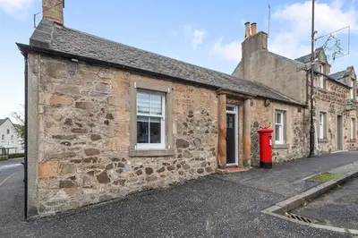 an old stone building with a red fire hydrant outside at The Post Office in Torphichen