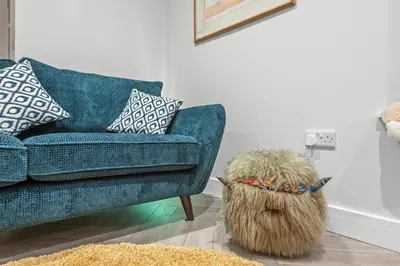 a living room with a blue couch and a dog at The Post Office in Torphichen