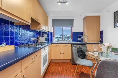 a kitchen with blue tiled walls and wooden cabinets at Modern 2 bedroom apartment in City Centre in Edinburgh
