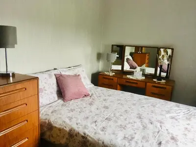 a bedroom with a bed with a dresser and a mirror at Farmhouse in Clydebank