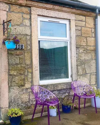 two purple chairs sitting in front of a building at Tin Lid Cottage - cosy ground floor flat in Banton