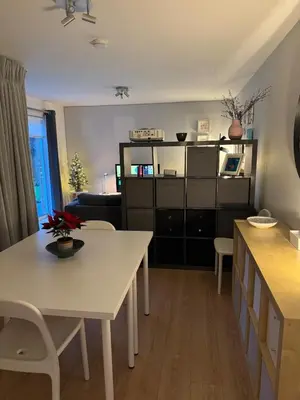 a living room with a white table and a kitchen at Spacious & Modern Garden Apartment in Bearsden