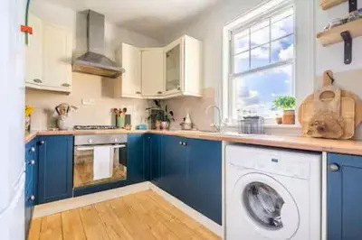 a kitchen with blue cabinets and a washing machine at Peace in the City in Edinburgh