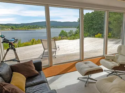 a living room with a large window view of a lake at Ferry House in Bonawe