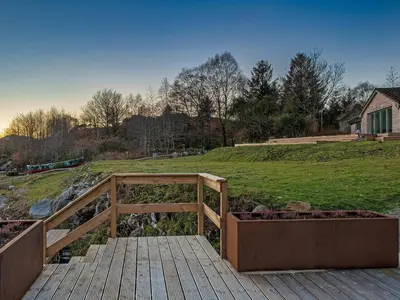 a wooden boardwalk leading to a yard with a field at Ferry House in Bonawe