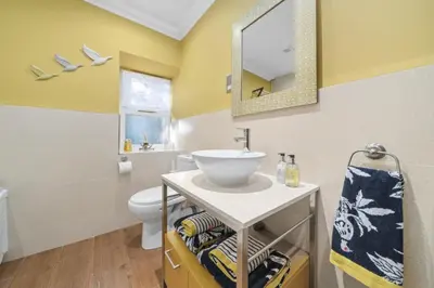 a bathroom with a sink and a toilet and a mirror at The Strone Luss Premium Holiday Rental in Luss