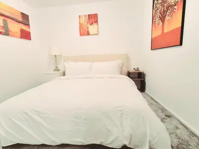 a white bed in a white bedroom with paintings on the wall at Cozy Flat in Glasgow City Centre in Glasgow