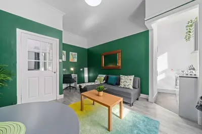 a living room with green walls and a couch and a table at Central Kirkintilloch 2 Bed App in Kirkintilloch