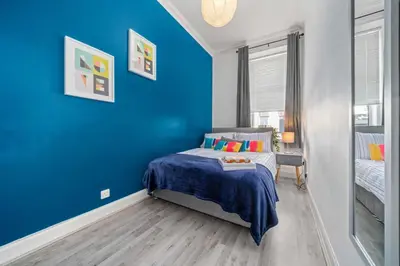 a blue bedroom with a bed with a blue wall at Central Kirkintilloch 2 Bed App in Kirkintilloch