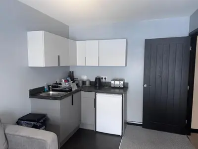 a small kitchen with white cabinets and a black door at Langside apartments 2 in Newhouse