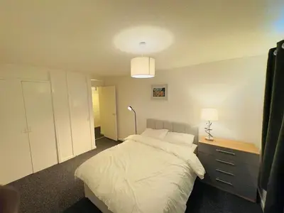 a bedroom with a white bed and a lamp at Cosy flat in Glasgow in Maryhill