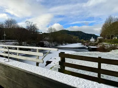 a bridge with a fence and a river with snow at Cosy Cottage with Woodburner by Crinan Canal Pets Welcome in Cairnbaan