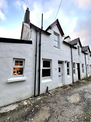 a white house with two windows on a street at Cosy Cottage with Woodburner by Crinan Canal Pets Welcome in Cairnbaan