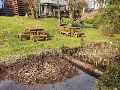 a group of picnic tables on the grass near a body of water at The River Inn in Killin