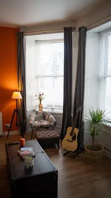 a living room with a guitar and a couch at 20min train to Edinburgh, The Coorie Inn in Inverkeithing