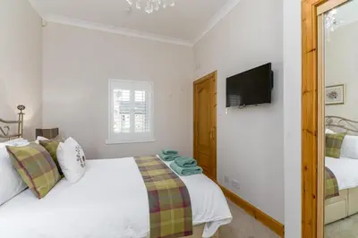 a white bedroom with a bed and a flat screen tv at 2 Bed in Rosyth oc-r30512 in Rosyth
