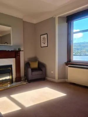 a living room with a fireplace and a chair and a window at Campbeltown Harbour View in Campbeltown