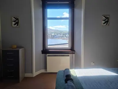 a bedroom with a window with a view of the water at Campbeltown Harbour View in Campbeltown