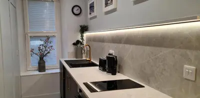 a kitchen with a sink and a clock on the wall at 17 Oban in Oban