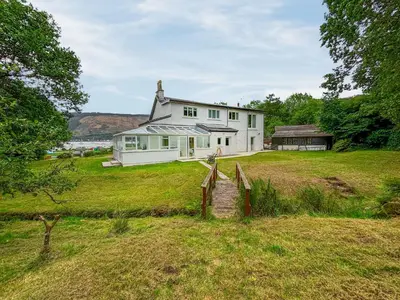 a white house on top of a grass field at Heatherdale in Dunoon