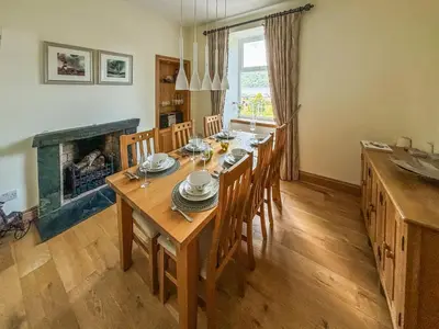 a dining room with a table and a fireplace at Heatherdale in Dunoon