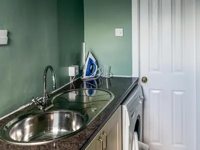 a bathroom with a sink and a green wall at Littlebay Apartment in Oban