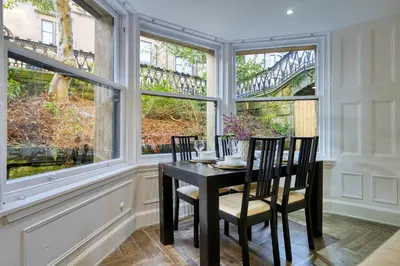 a dining room with a table and chairs and windows at Stylish 3-Bedroom Apartment in Central Glasgow in Glasgow