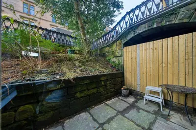 a chair sitting next to a stone wall with a bridge at Stylish 3-Bedroom Apartment in Central Glasgow in Glasgow