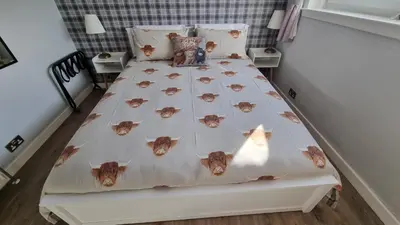 a bedroom with a bed with a cow comforter at Innisfail Edi - double room with private bathroom in Edinburgh