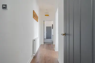 a hallway with white walls and a wooden floor at Spacious 3 bed flat- Free parking Edinburgh & Fife in Inverkeithing