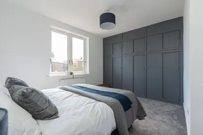 a bedroom with a large bed and a window at Spacious 3 bed flat- Free parking Edinburgh & Fife in Inverkeithing