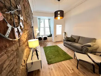 a living room with a couch and a green rug at Stunning refurbished main door Marchmont apartment in Edinburgh