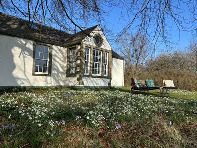 a house with a bench and flowers in front of it at Gorgeous boutique off-grid cottage near Peebles in Peebles