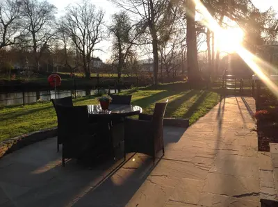 a table and chairs in a park with the sun shining at Lovely Riverside Holiday Home in Callander