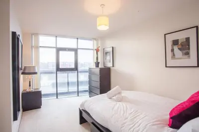 a white bedroom with a bed and a large window at Apartment with river view next to hydro in Glasgow